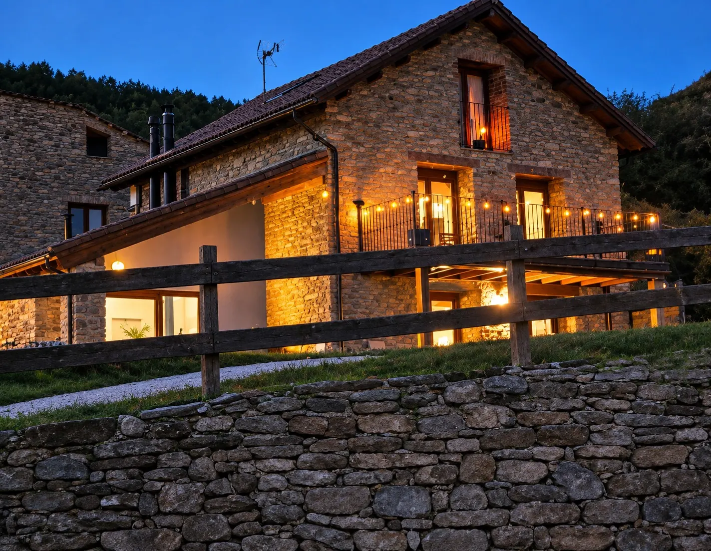 La casa iluminada al anochecer junto a la valla de madera