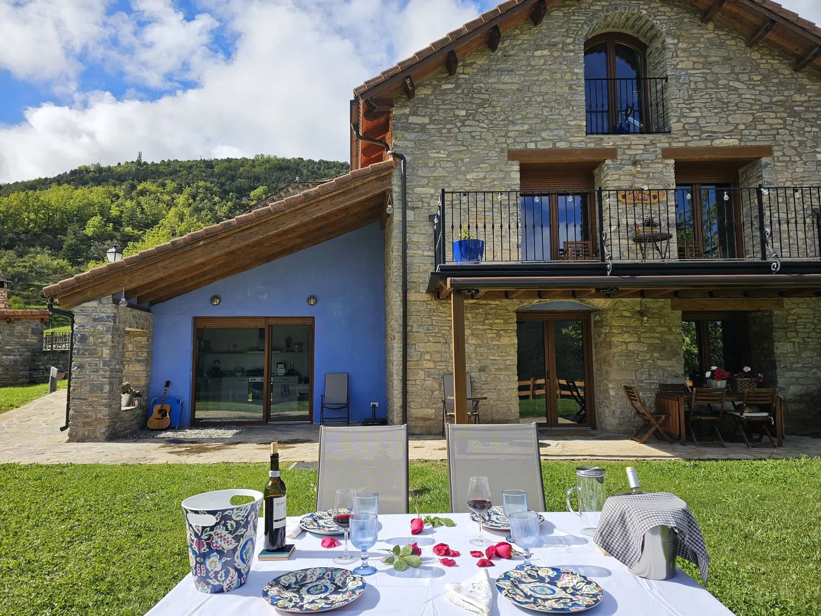 Fachada de piedra con balcón de madera y pared azul